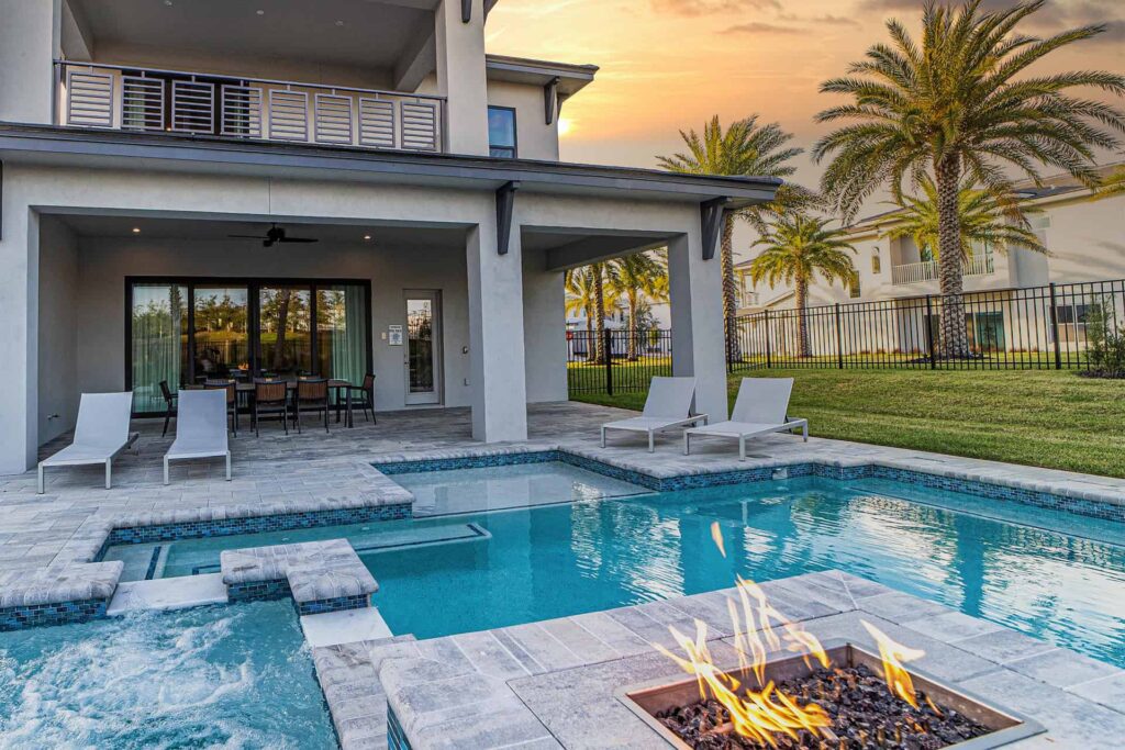 Luxury vacation home backyard with pool, hot tub, fire pit, covered lanai, and balcony