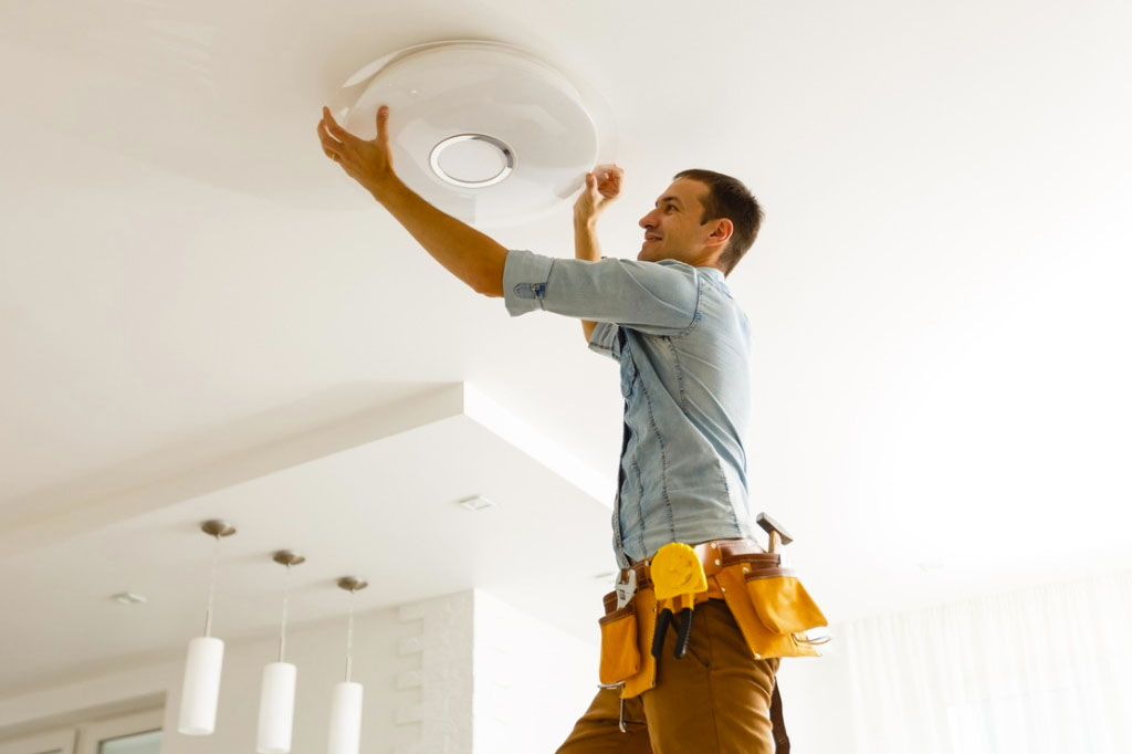 Homecare maintenance specialist changing a ceiling light bulb